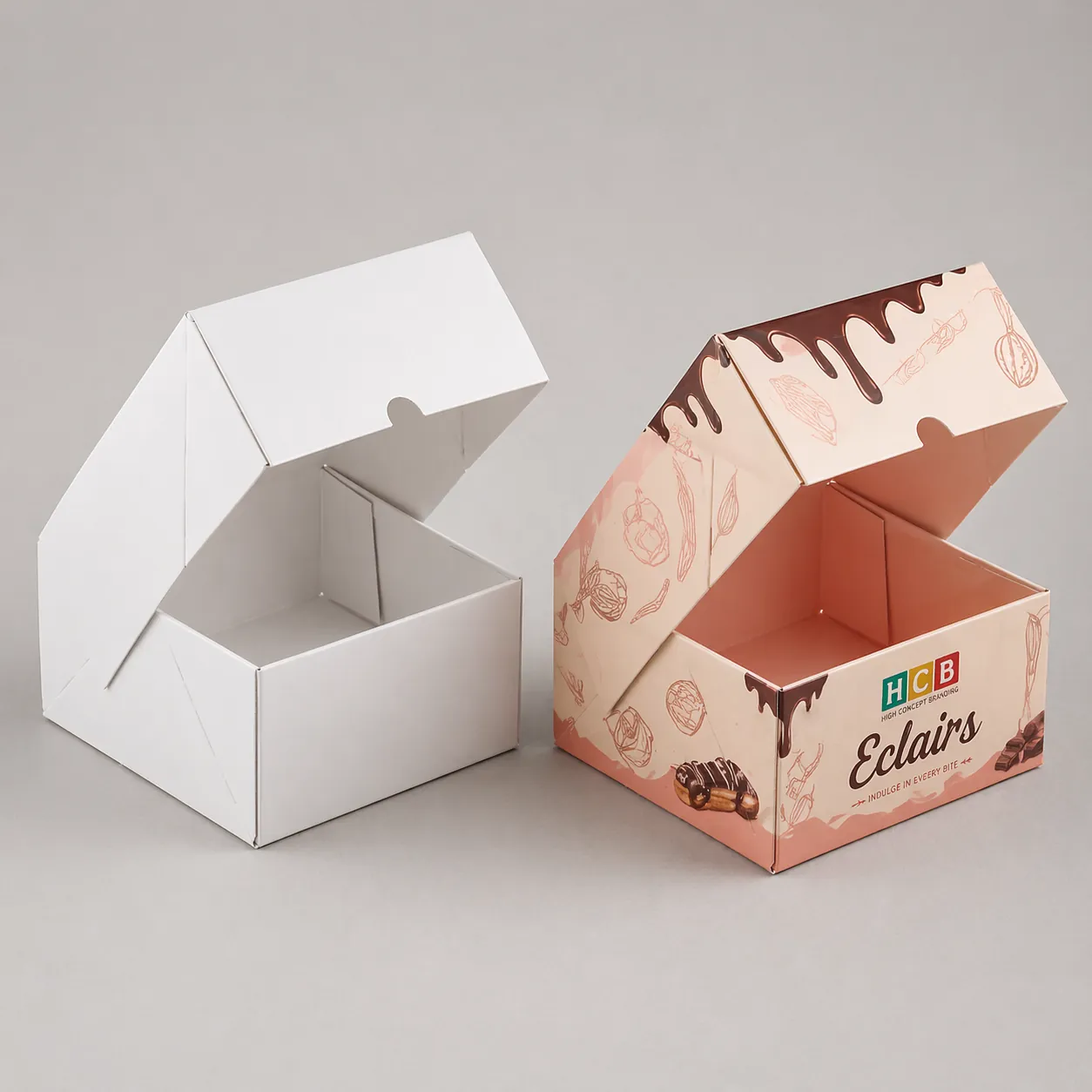 Two rectangular boxes with large top window cutouts displaying rows of fresh chocolate glazed éclairs.